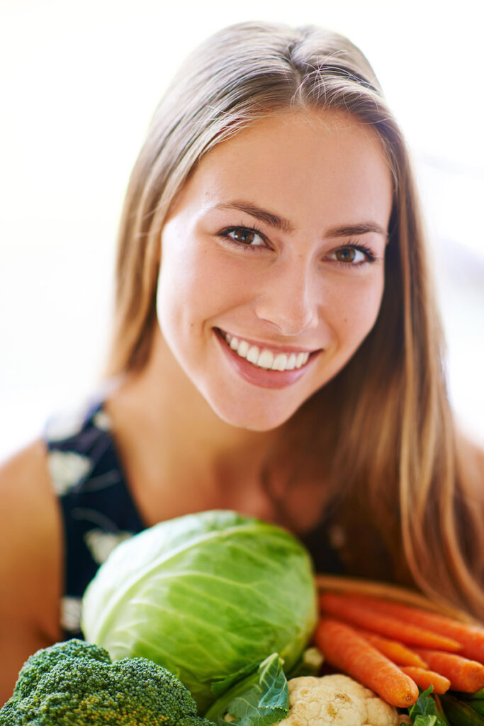 Happy, portrait and woman with vegetables on kitchen counter for health, nutrition and wellness. Smile, nutritionist and groceries for diet, vegan and home in apartment for meal prep and cooking.