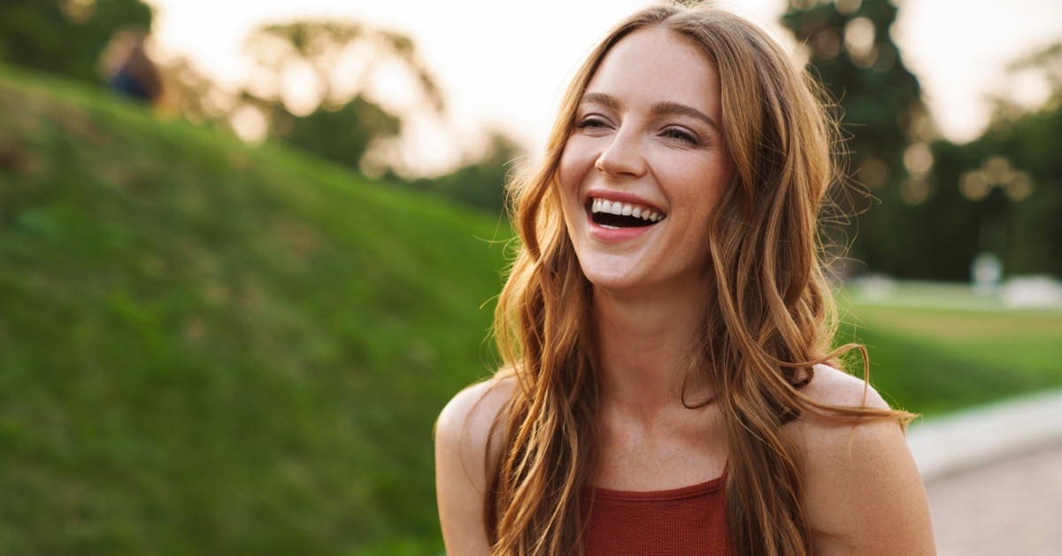 Photo of a happy laughing emotional young woman walking in nature green park outdoors.