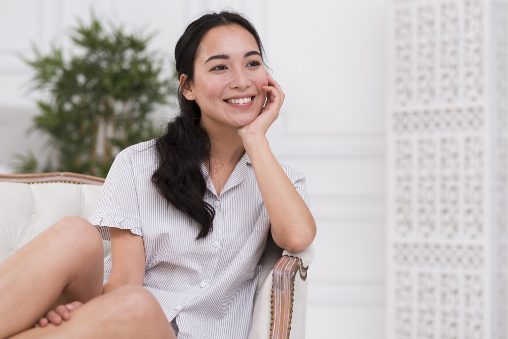 happy smiling woman sitting on the couch in her pajamas